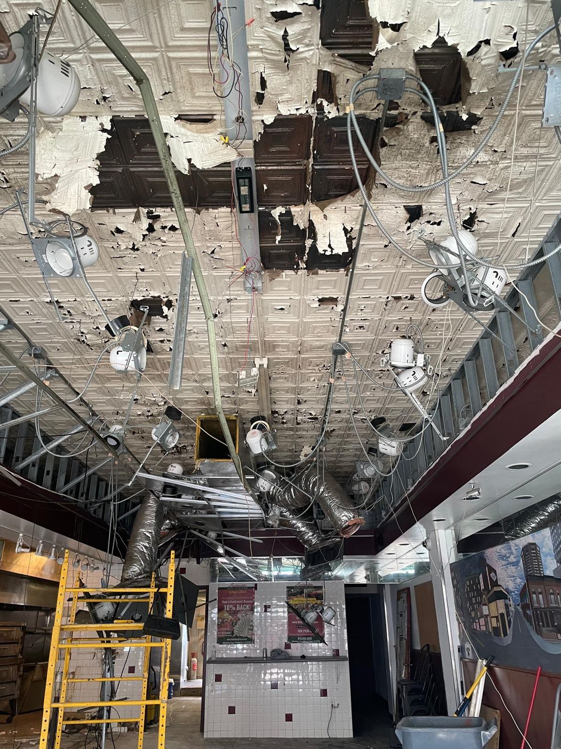 Ceiling removed during strip-out, ductwork and conduit exposed above the floor