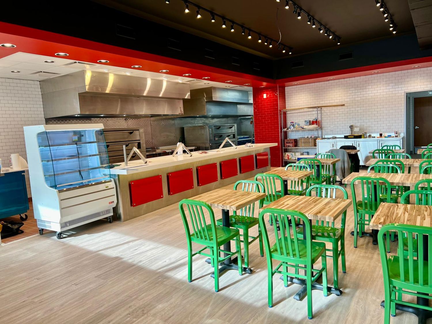 Wide view of the finished space showing the display case, cooking line and dining seating