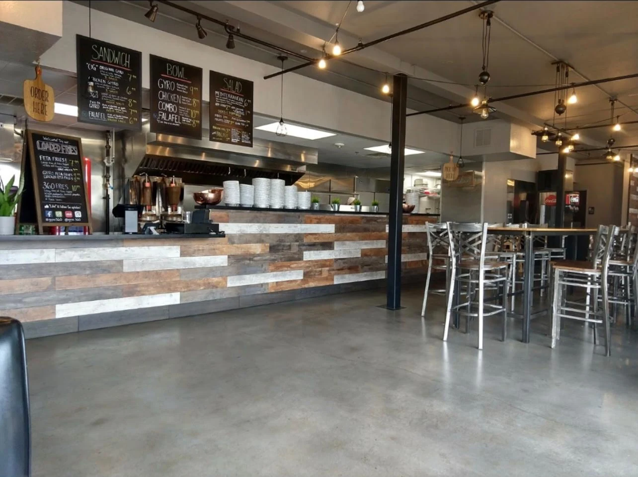 Completed Gyro 360 order counter with reclaimed timber cladding, chalkboard menus and industrial lighting
