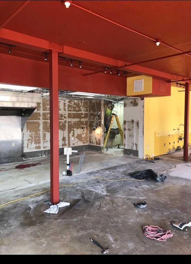 The same space during construction, ceiling stripped to the joists and services exposed