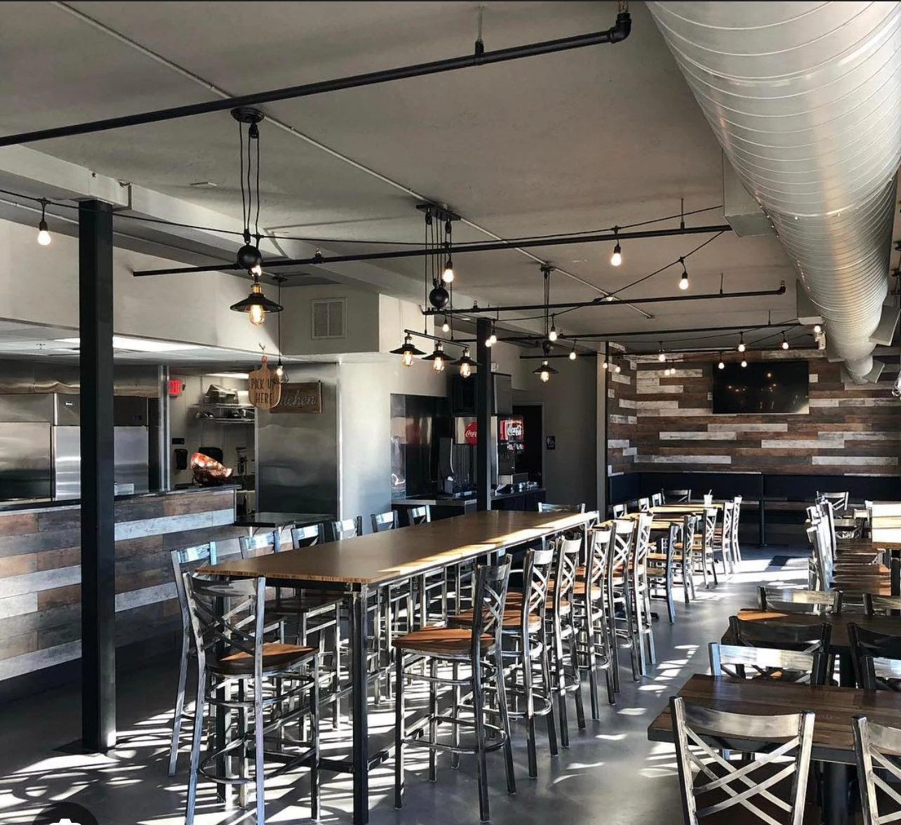 Completed Gyro 360 dining room with communal tables, pendant lighting and exposed ductwork
