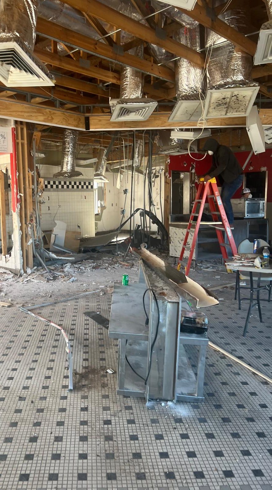 The same interior during demolition, stripped back to joists and ductwork with the old finishes removed